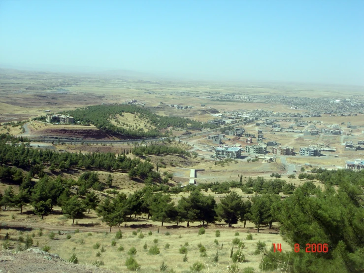 a landscape s of an area with many trees and a small town in the distance