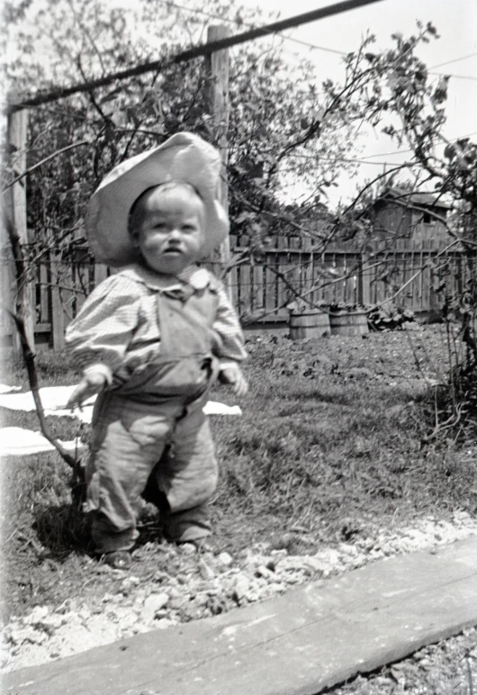 the small child is wearing a hat and carrying a toy