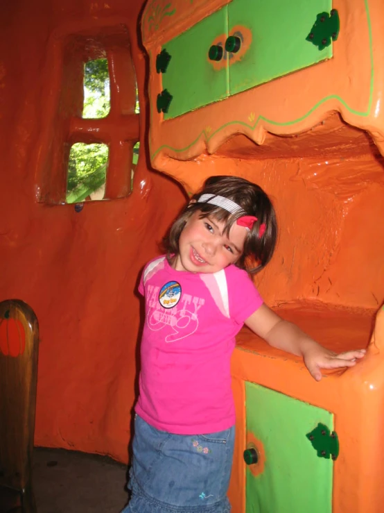 a girl standing inside of a play area with colorful furniture