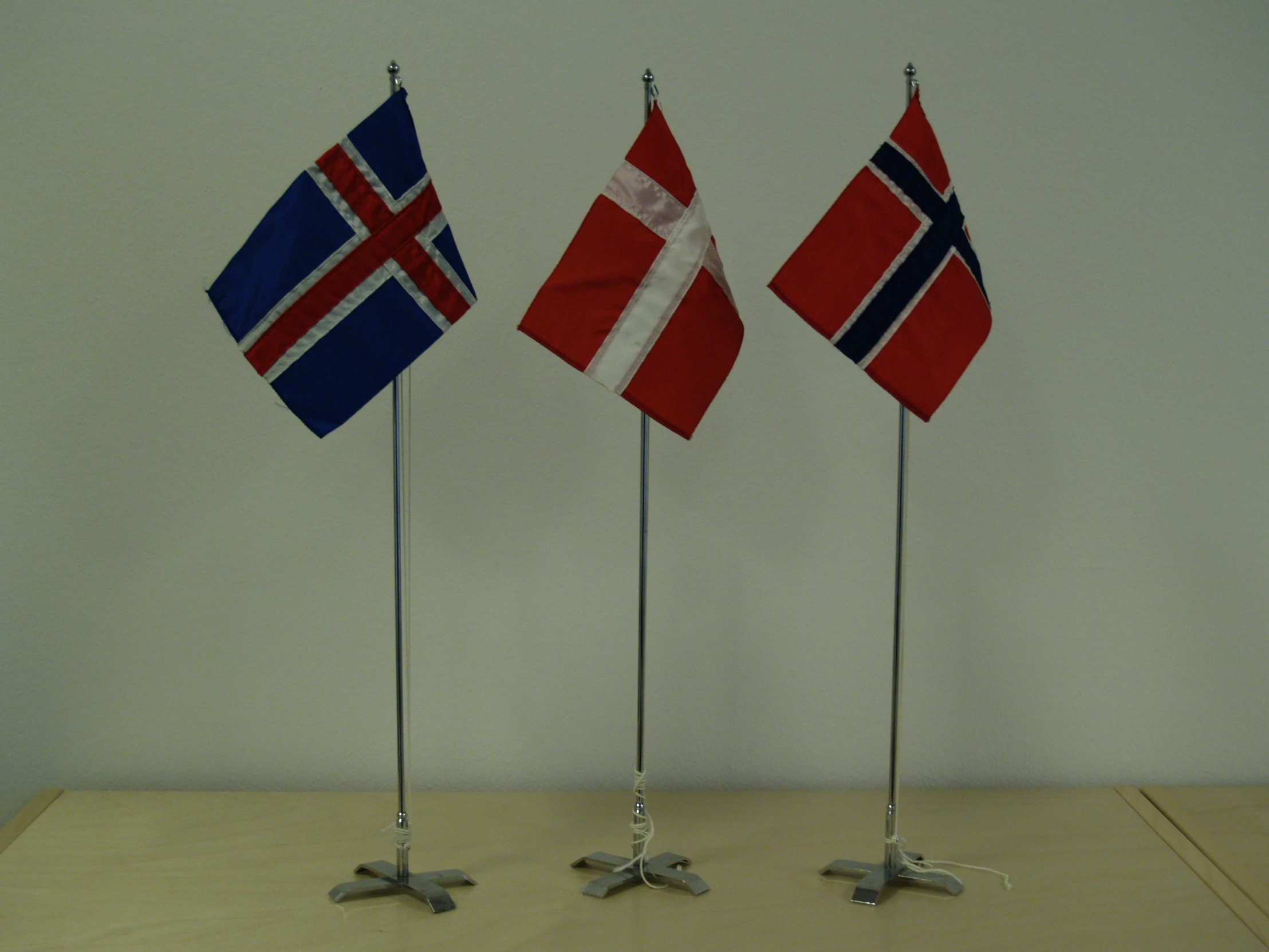 three miniature flags of different countries on metal poles