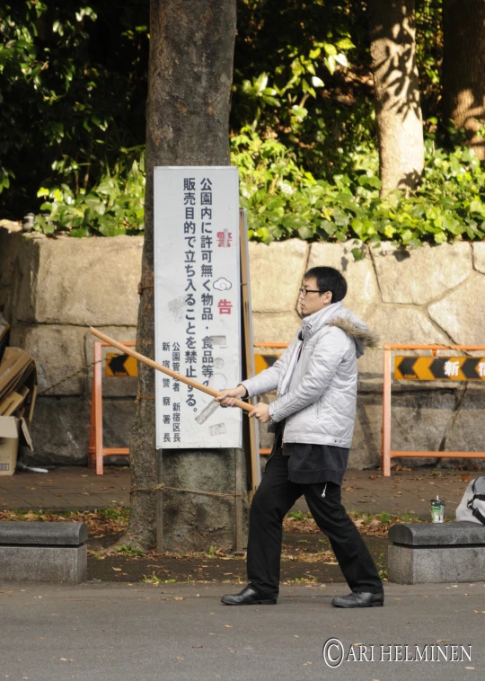 a man in glasses is holding a stick near a tree