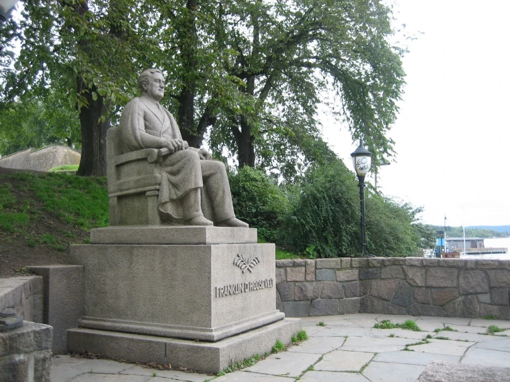 an outdoor park has a bench with a statue next to it