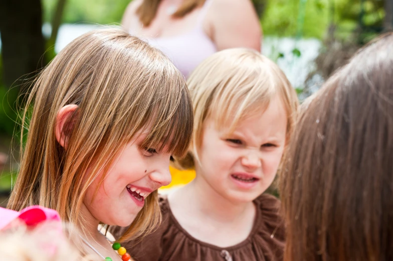 two young children laugh as they stand side by side