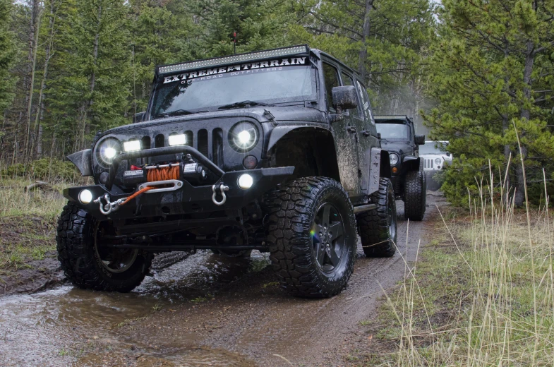 a dark jeep with lights on is traveling down the road