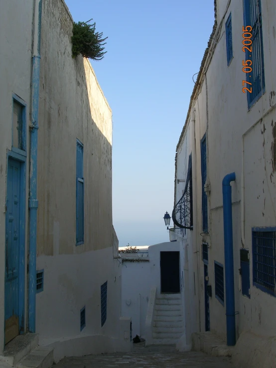 an alley way with several windows and blue shutters