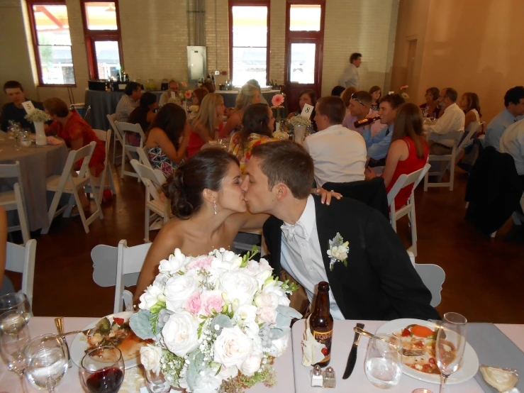 a bride and groom kiss in the middle of an elegant banquet