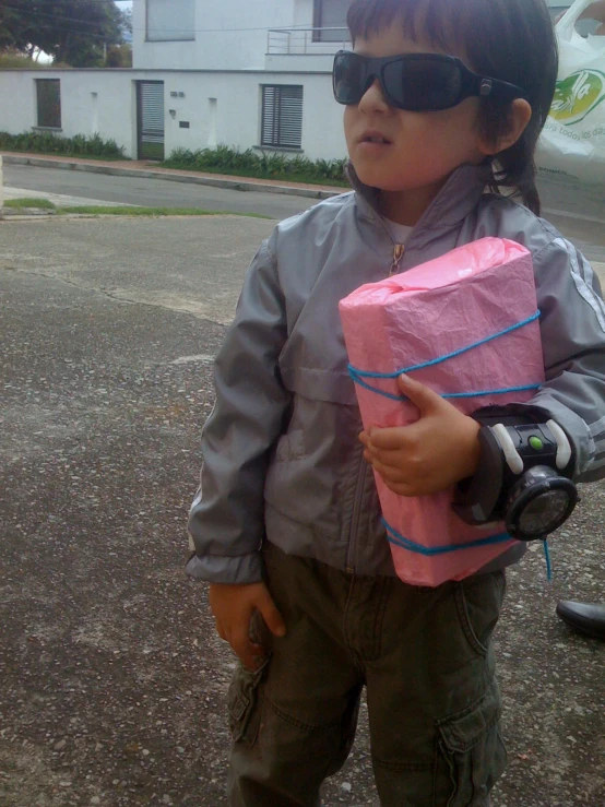 a  wearing sunglasses and holding pink paper wrapped present