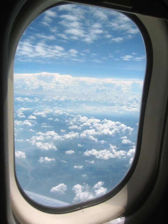 an airplane window shows a cloudy sky as it is seen