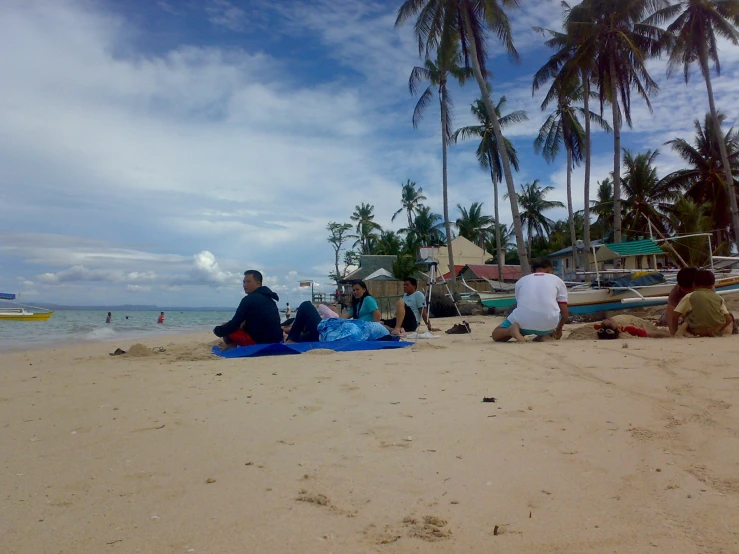 several people on a beach by water and boats