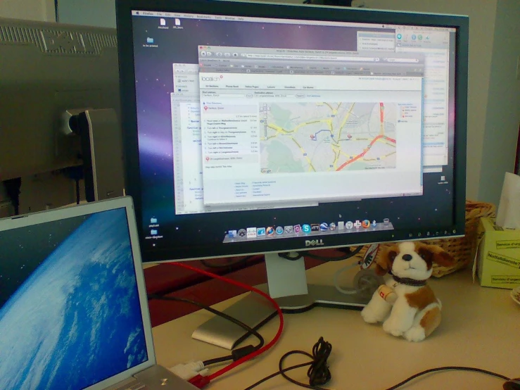 a laptop computer sitting on a desk with a stuffed dog and monitor