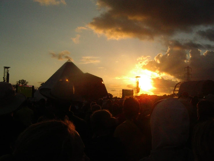 a large group of people sitting in front of a sunset