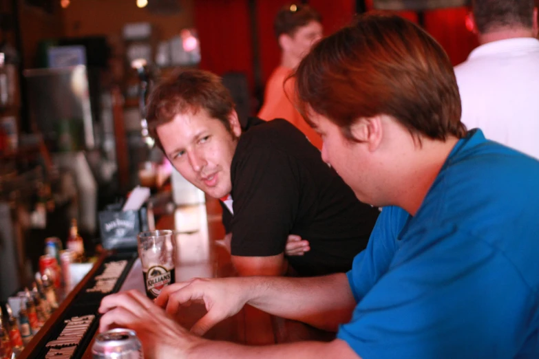 a man sitting in front of a bar next to another person at a counter