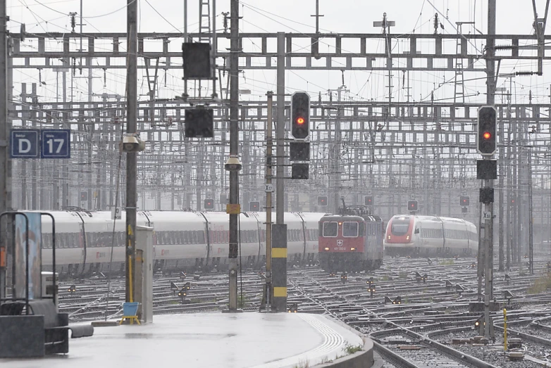 multiple train tracks with many trains and a person standing on the platform