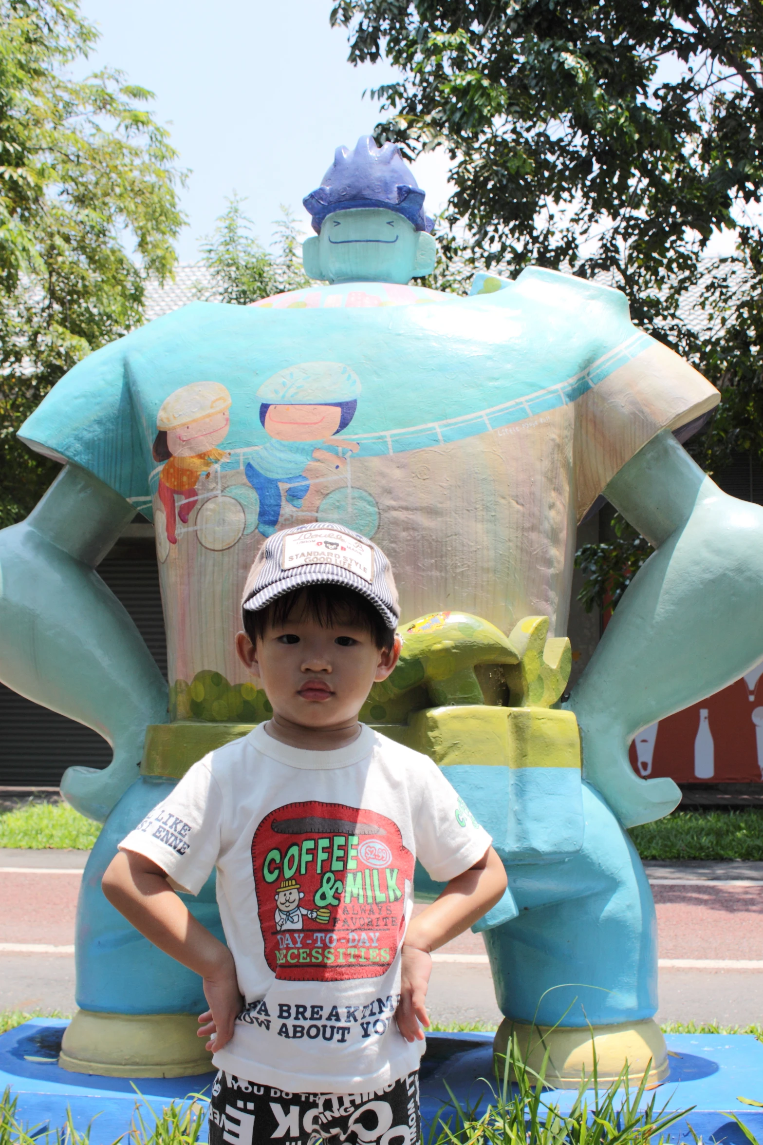 a  in a t - shirt and baseball cap stands in front of an inflatable animal