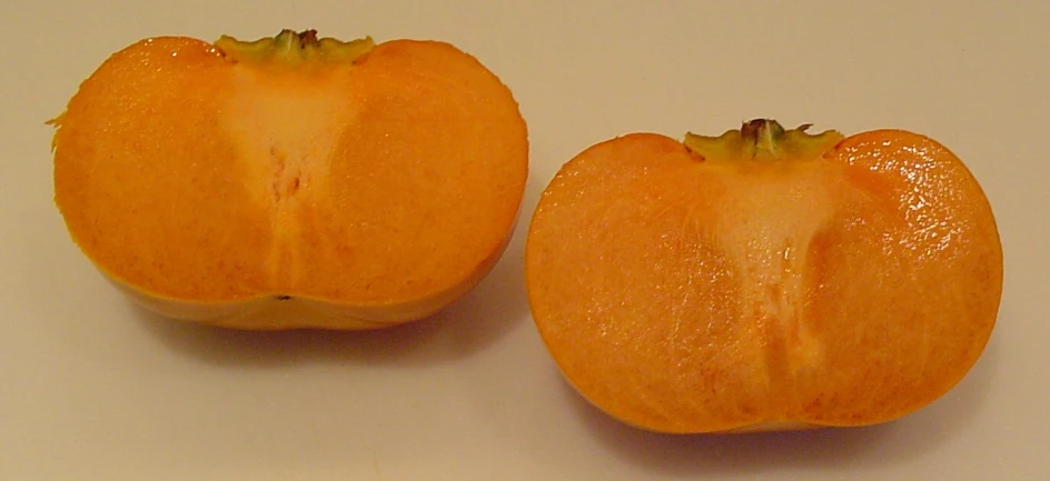 two pieces of orange fruit sitting on top of a table