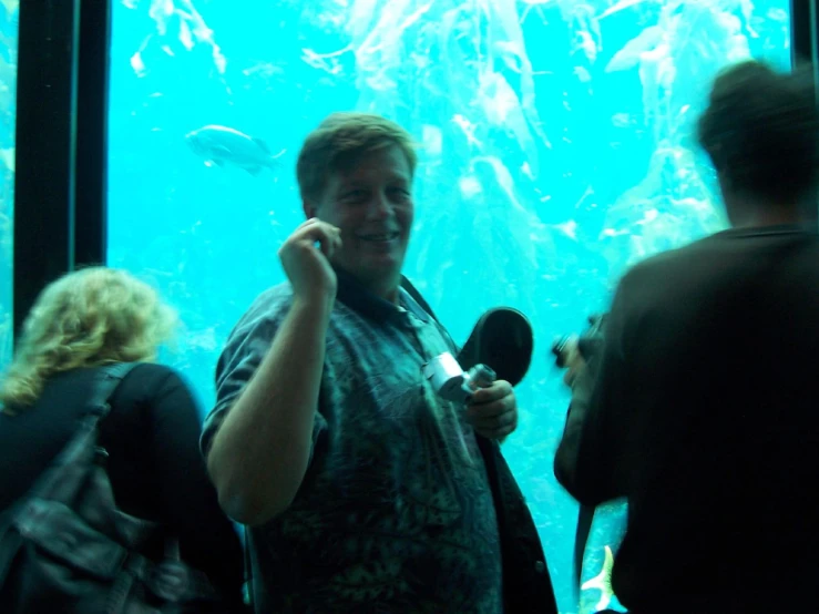 a man is smiling as he looks at the fish in a large tank