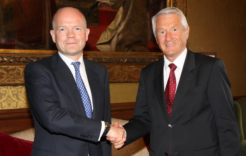 two men shaking hands in an elegant setting