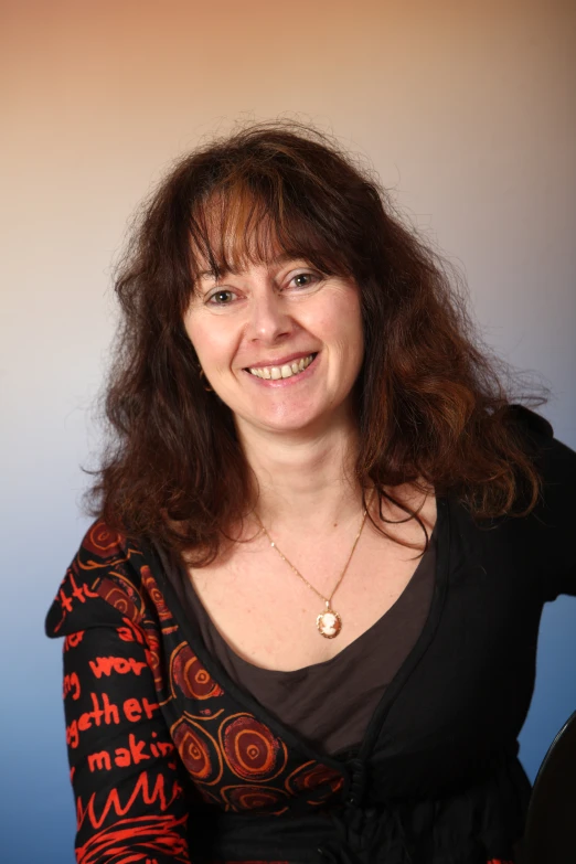 woman smiling with dark long hair in front of blue background