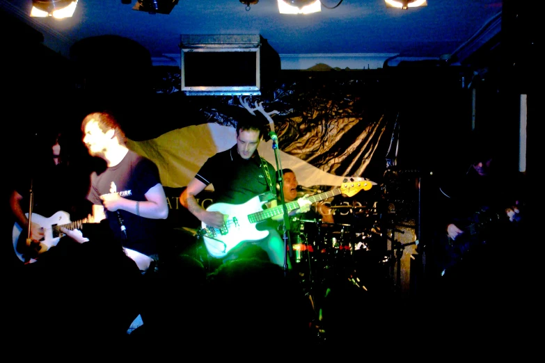 two people playing guitar in a dark room