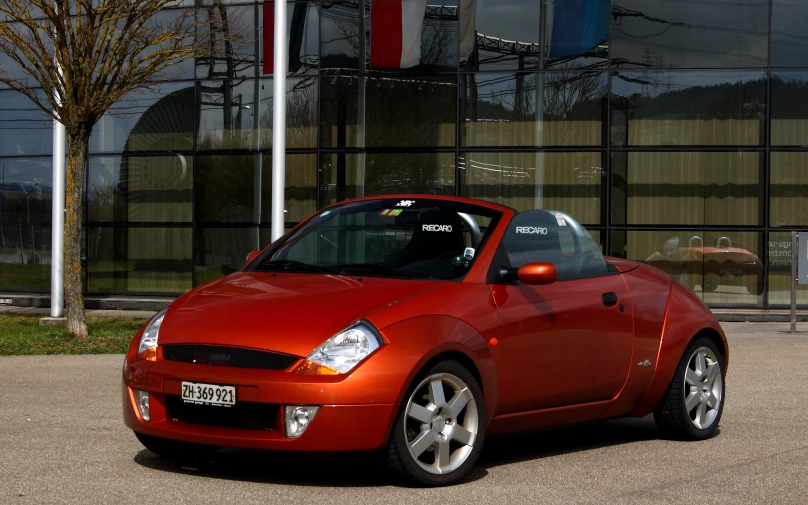 the small red car is parked in the lot