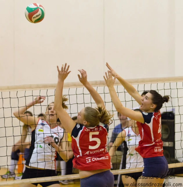 women play volleyball in red, white and blue uniforms