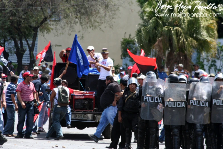 a bunch of police officers stand near a vehicle with flags