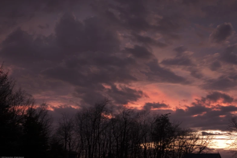 sunset with clouds over trees and the sky in color