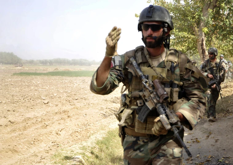 a man in uniform walking away holding his fist up to the camera