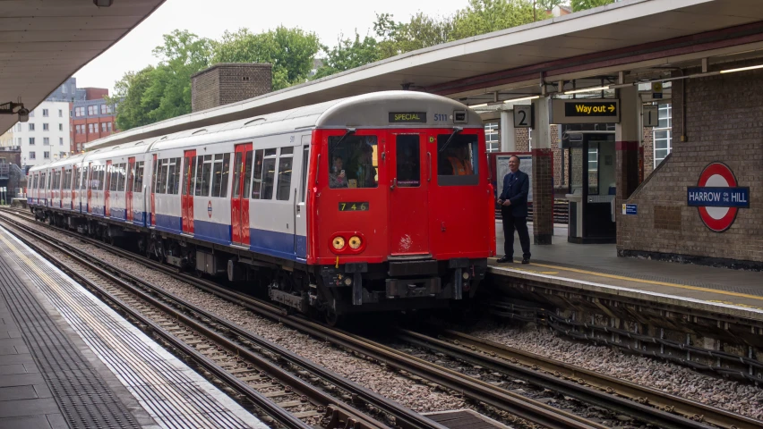 a train pulls up to the station where a man is waiting