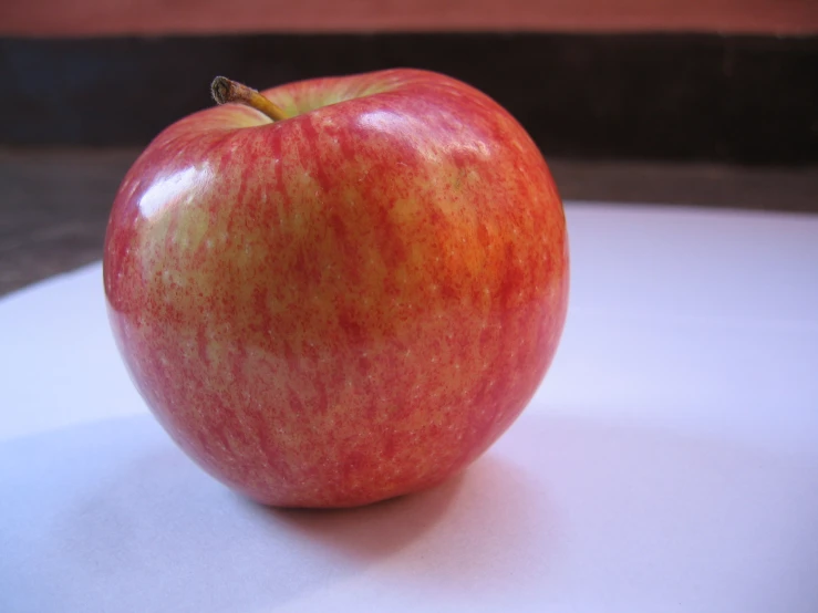 a single red apple sitting on top of a table