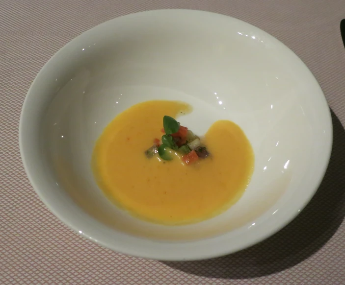 a bowl filled with broth and vegetables on a beige cloth