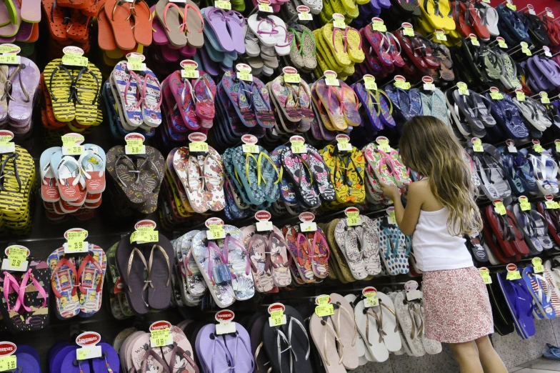 a girl is looking through some sandals for sale