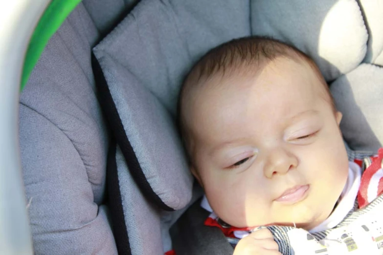 a baby sleeping in a car seat with a blanket over his face