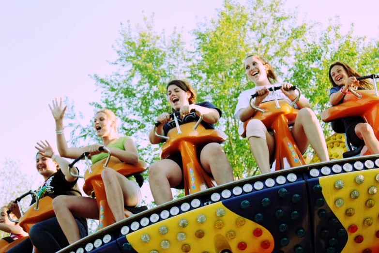 the women are wearing orange dresses while riding the roller coaster