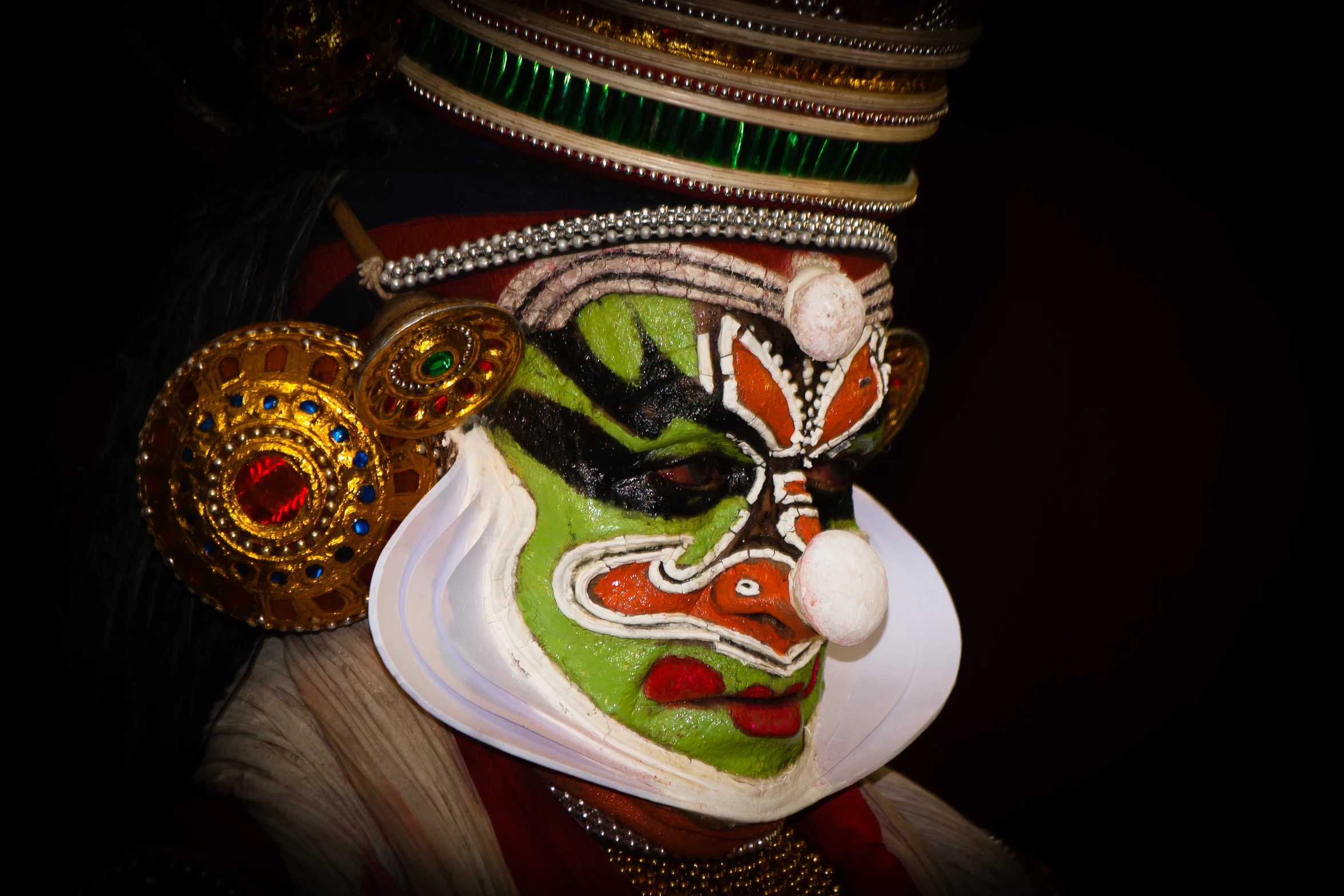 a man with green face paint and colorful costume