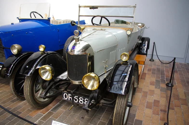 an old time car and a newer one in a museum