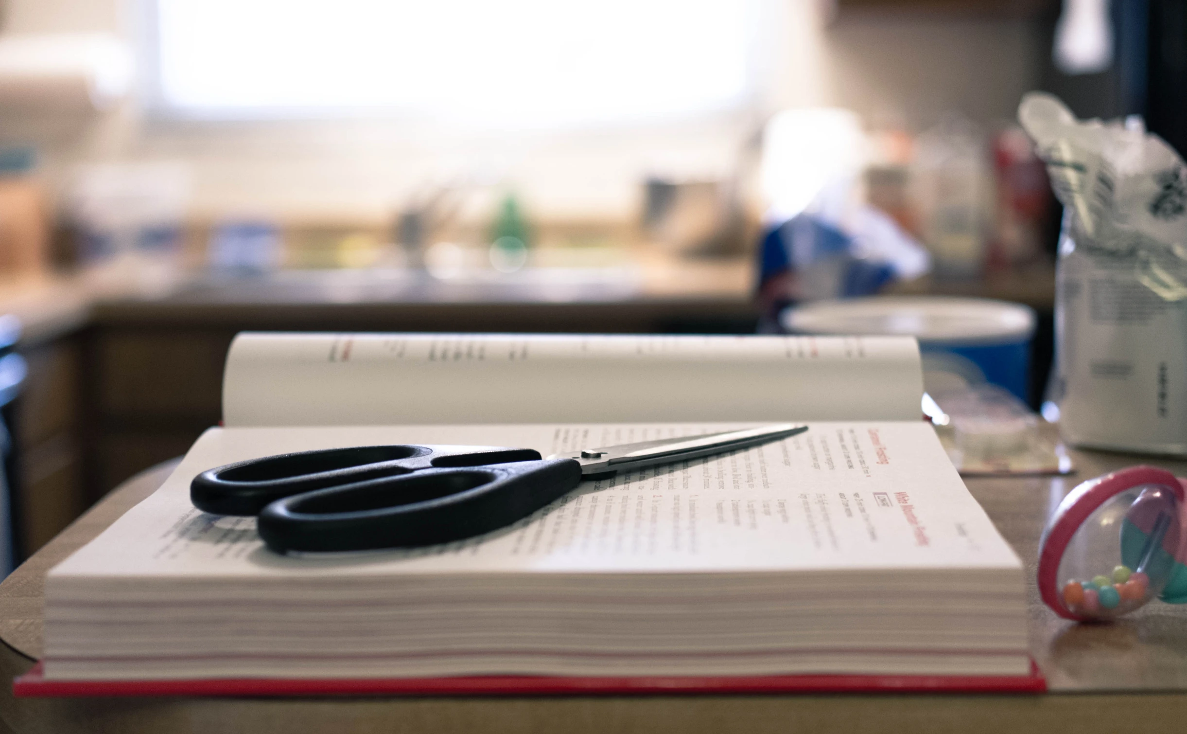 a closeup of a pair of black scissors resting on a notebook with papers