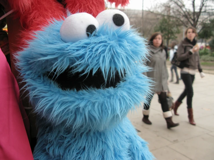 a stuffed animal with big eyes next to other people