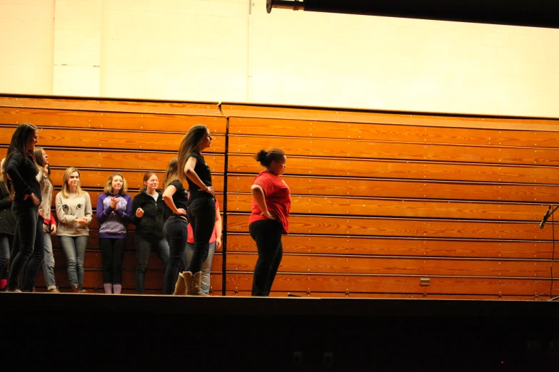 three girls on the stage, with some onlookers watching