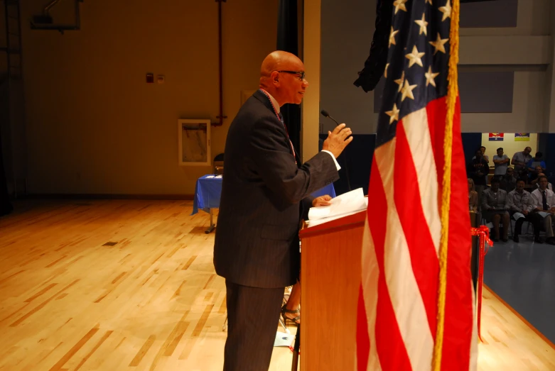 a man standing at a podium with an american flag