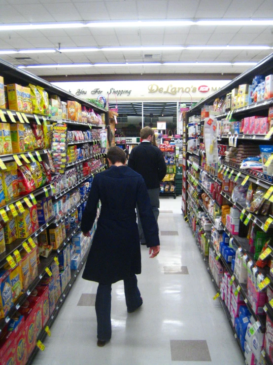 two people are walking in a supermarket aisle