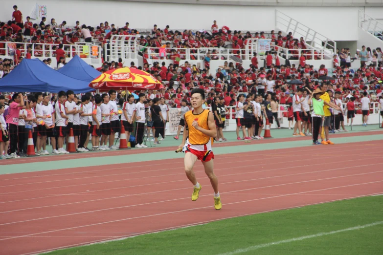 an asian athlete crosses the track on her knees as a crowd looks on