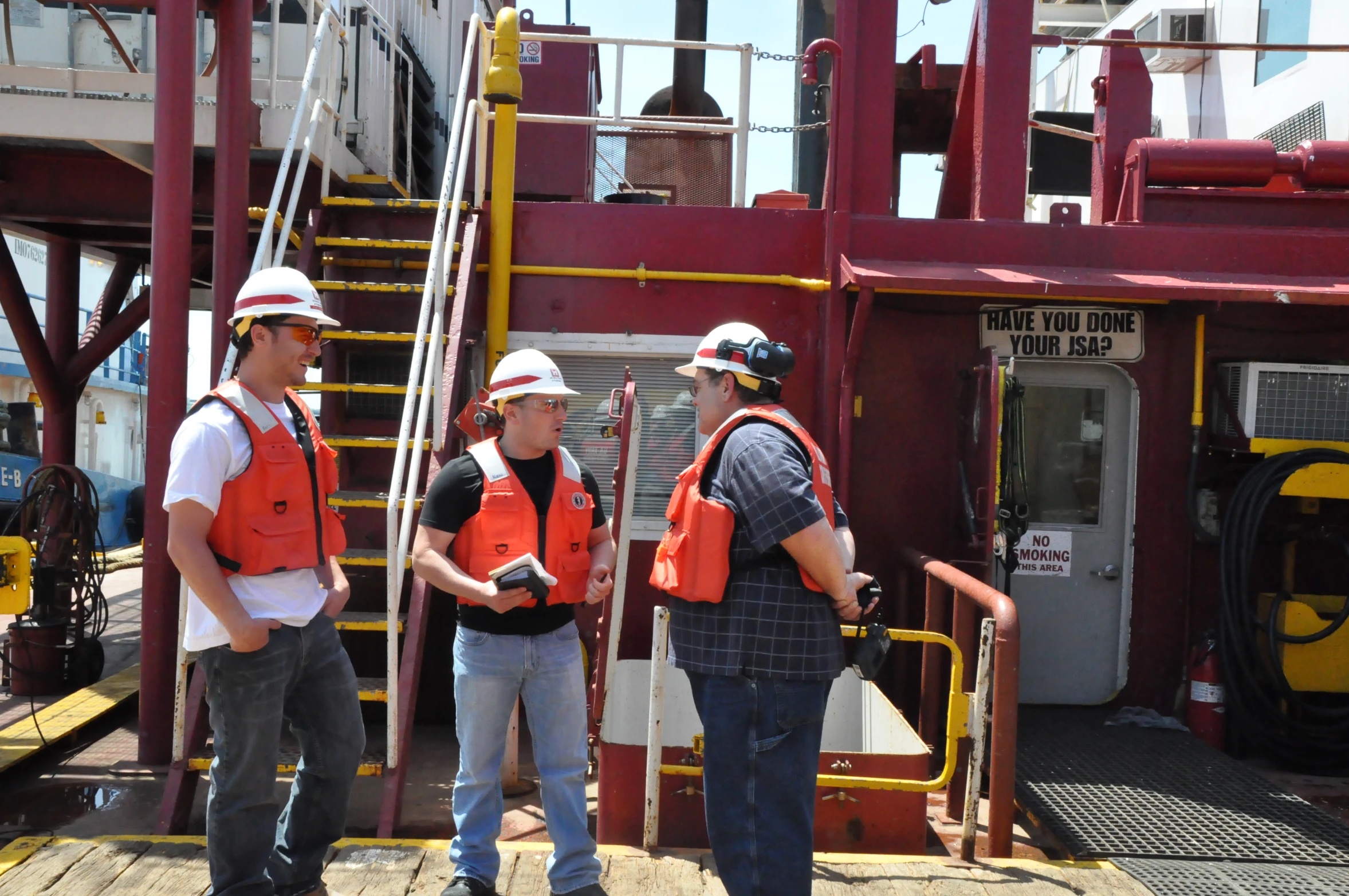 three men wearing safety vests on a boat