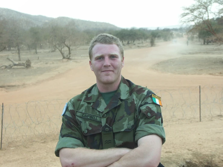 man in camouflage clothes standing in front of barbed wire