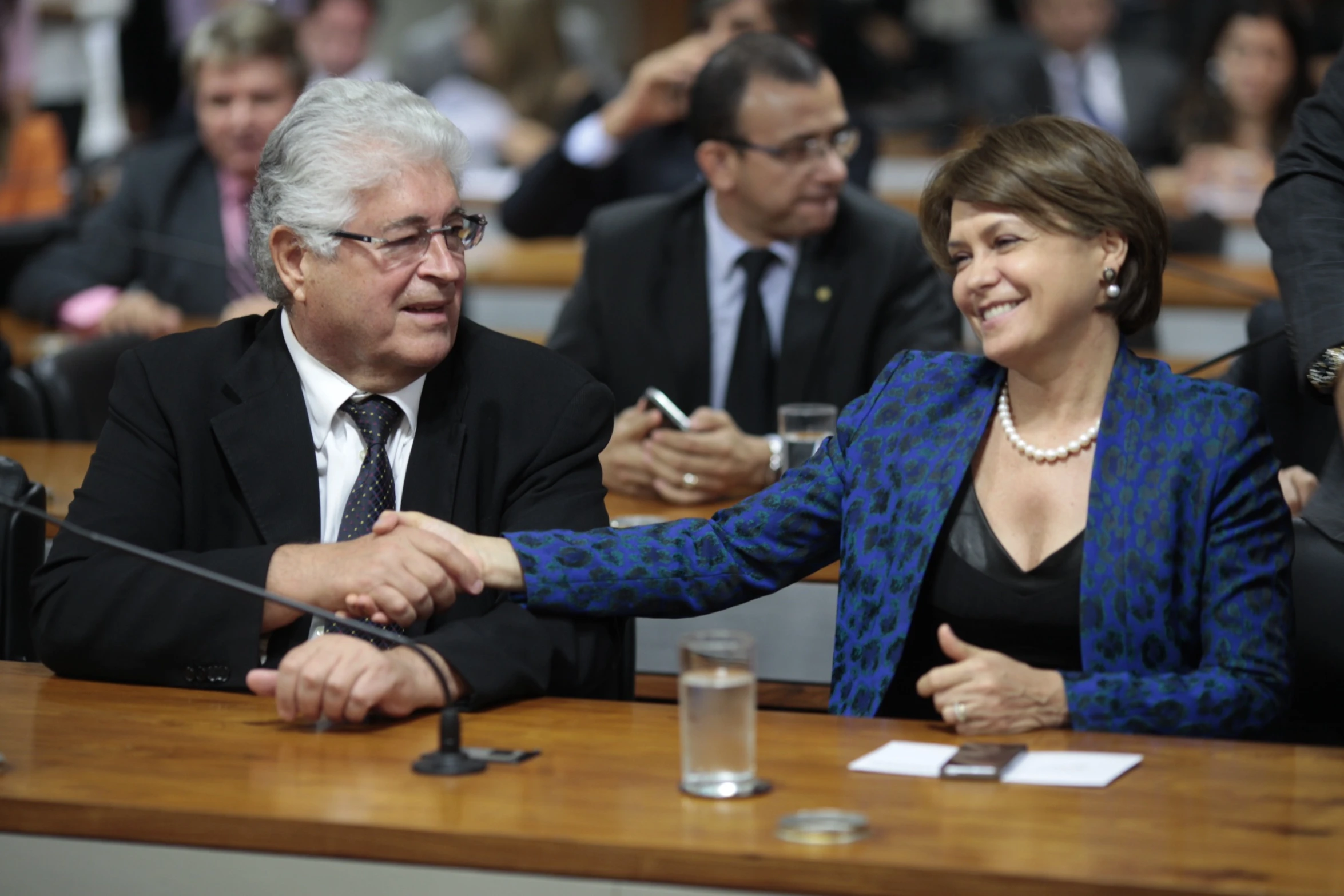 a group of people at a meeting, with people in the background clapping