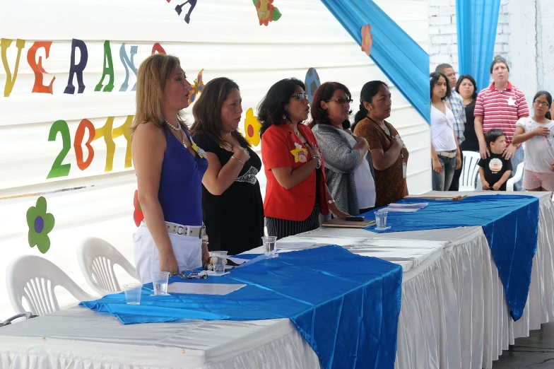 young women stand around a long table covered in white plastic