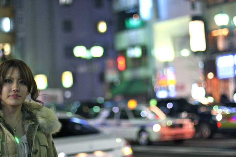 a woman standing on the street in front of a bunch of parked cars