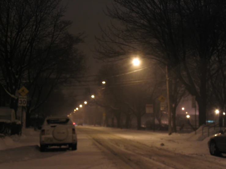 a white car parked in the snow on a road