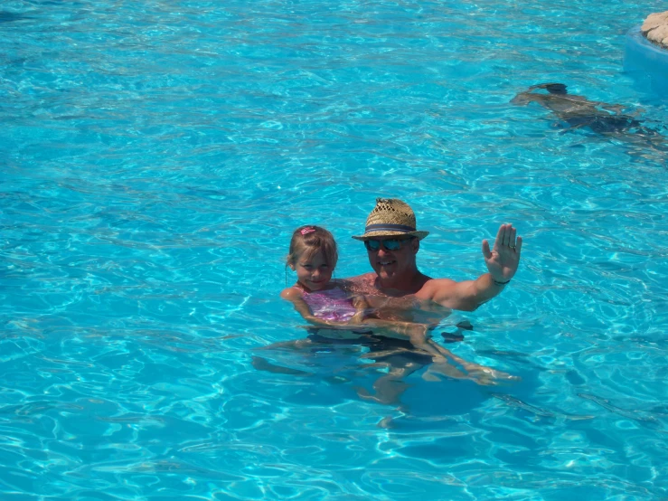 man and little girl playing in water at the pool