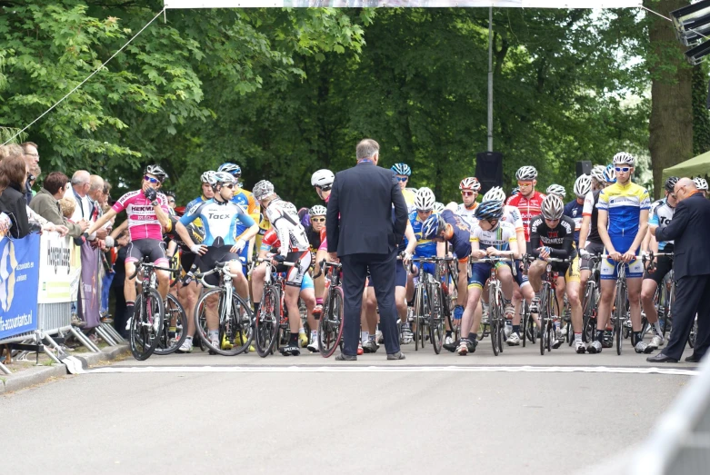 a group of cyclists going down the road next to a crowd